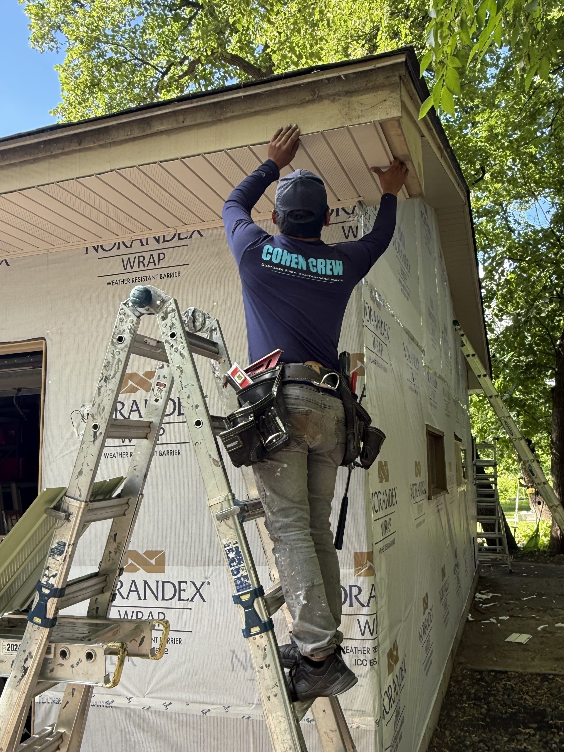 Cohen Construction crew member fitting soffit over Norandex weather barrier on a St. Michael, MN home